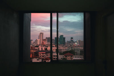 Buildings against sky seen through window