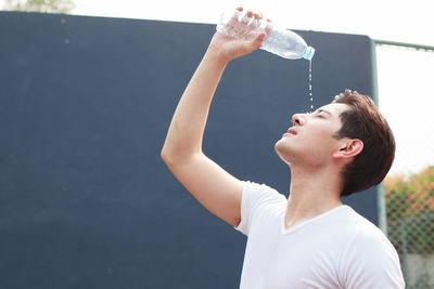 Young man pouring water on face