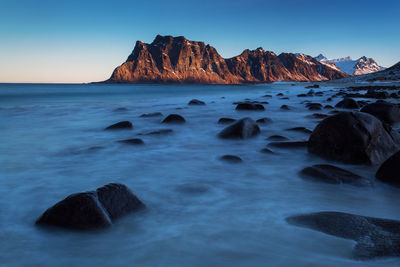 Rock formation in sea against clear sky