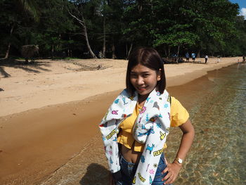 Portrait of smiling young woman standing on beach