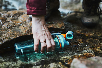 Woman taking pure water to bottle from mountain stream during trekking in mountains
