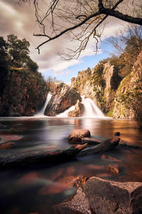 Scenic view of waterfall against sky