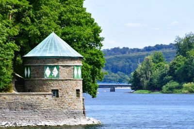 House by lake against sky