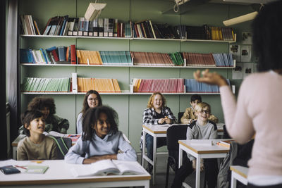 Smiling students attending lecture sitting at desk in classroom