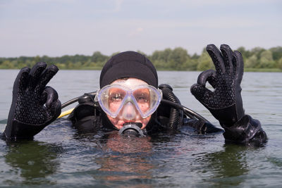 Portrait of scuba diver with ok sign in lake