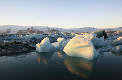 Ice floating on water against sky during winter