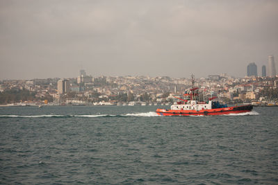 Boats in sea with city in background