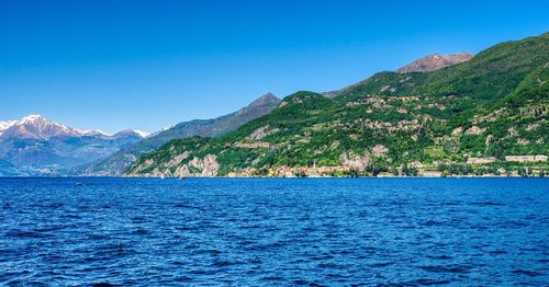Scenic view of sea and mountains against clear blue sky