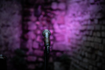Close-up of microphone against illuminated purple wall