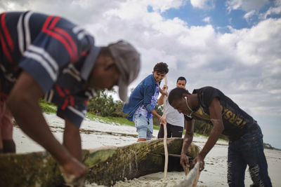 Group of young fishermen repair boat at africa beach.