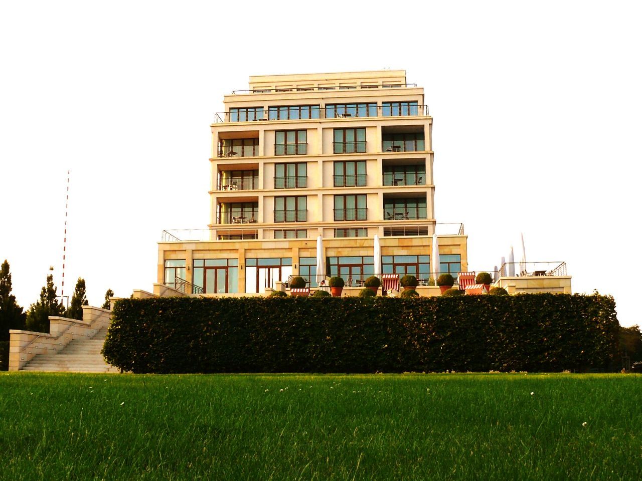 building exterior, architecture, clear sky, built structure, grass, copy space, lawn, green color, city, incidental people, building, men, day, outdoors, sky, grassy, walking, tree, facade