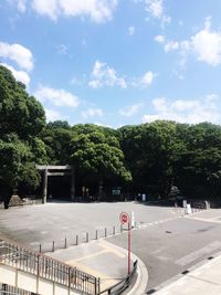 Trees on road against cloudy sky