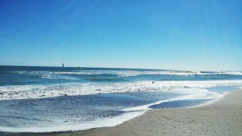 Scenic view of beach against clear blue sky