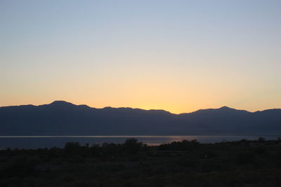 Scenic view of silhouette mountains against clear sky during sunset