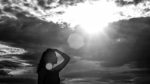 Woman standing against cloudy sky