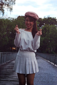 Portrait of happy young woman standing on footbridge