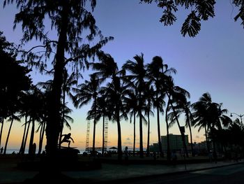 Silhouette palm trees on beach against clear sky