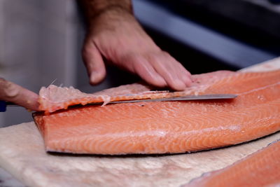 Cropped hands slicing salmon