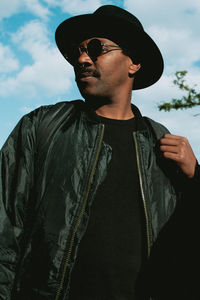 Low angle view of man wearing sunglasses standing against sky