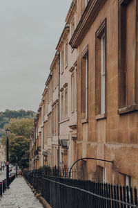 Street view of a row of old stone terraced houses on a street in bath, somerset, uk.