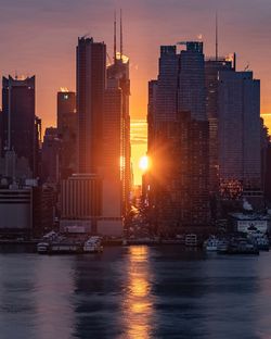 Modern buildings in city against sky during sunset