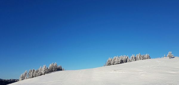 Low angle view of snow against clear blue sky