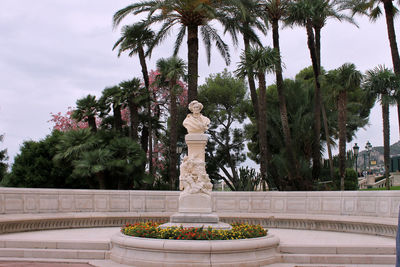 Statue by palm trees against sky