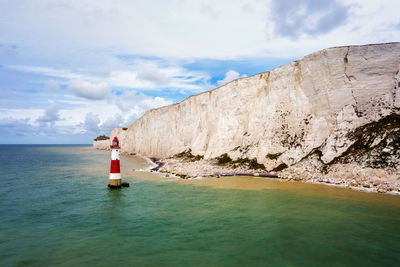 Lighthouse by sea against sky