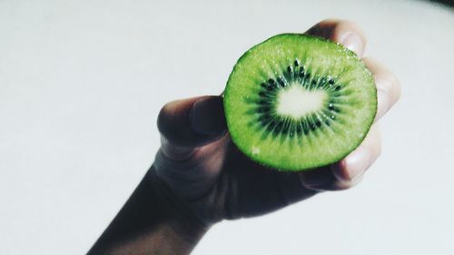 Close-up of hand holding apple against white background