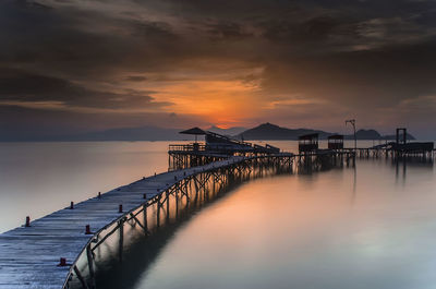 Pier over sea against sky during sunset