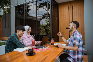 Side view of female friends working at table