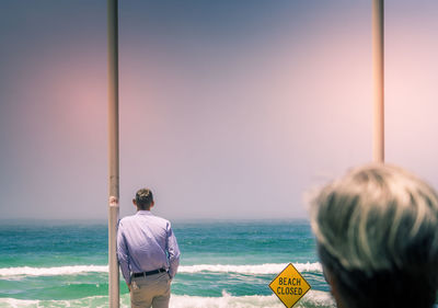 Rear view of men on beach against clear sky