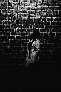 Rear view of woman walking against brick wall