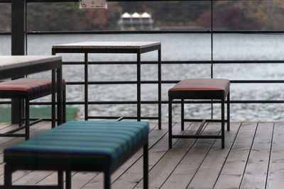 Empty chairs and tables in restaurant by lake