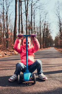 Cute girl sitting on electric push scooter on road