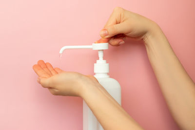 Close-up of person holding hands against pink background