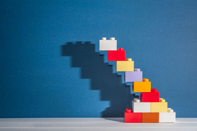 Stack of multi colored pencils on table against blue background