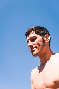 Portrait of shirtless man against clear blue sky