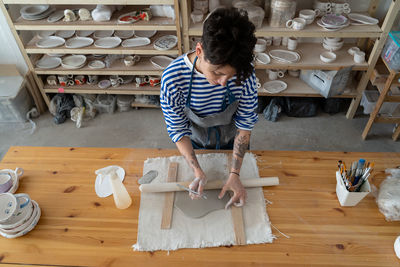 Female french artist work with clay on pottery table in creative art space