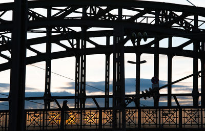 Silhouette people standing at construction site against sky