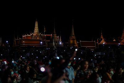 Crowd at illuminated temple against buildings at night