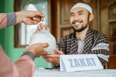 Young man helping with rice bag at mosque