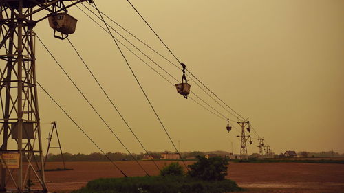 Low angle view of overhead cable cars against clear sky