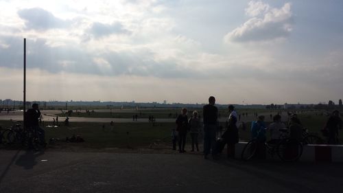 People on road against cloudy sky