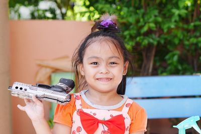 Portrait of cute girl holding toy gun