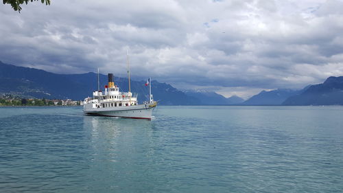 Ship sailing in sea against cloudy sky