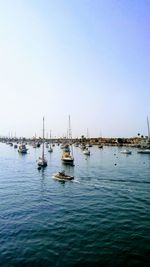 Boats sailing in sea against clear sky