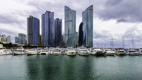 Sailboats in city by buildings against sky