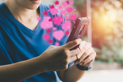 Midsection of woman holding smart phone outdoors