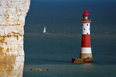 Lighthouse by sea against sky